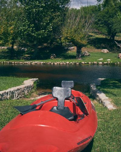 a red boat sitting in the grass next to a body of water at Los Ancares Resort in Mina Clavero
