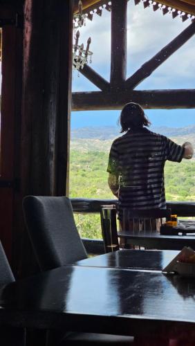 a person sitting at a table looking out of a window at Los Ancares Resort in Mina Clavero