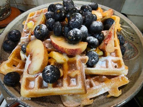 a plate of waffles with fruit and syrup at Blea Tarn Farmhouse B&B in Ambleside