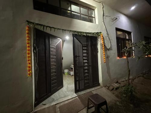 Un edificio con dos puertas abiertas y un taburete. en Nidhivan Vatika Ashram, en Vrindāvan