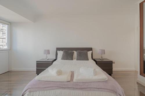 a bedroom with a large bed with two towels on it at On The Beach Penthouse with Sea View - 3 bedrooms - Roof Balcony - Spa, Sauna, Gym and Pool - Sleeps 6 in Brighton & Hove