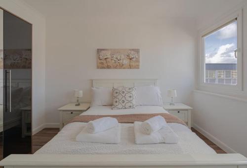 a white bedroom with a large bed with two windows at On The Beach Penthouse with Sea View - 3 bedrooms - Roof Balcony - Spa, Sauna, Gym and Pool - Sleeps 6 in Brighton & Hove