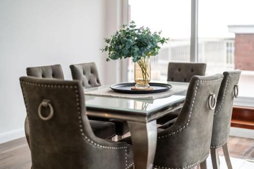 a dining room table with chairs and a vase of flowers at On The Beach Penthouse with Sea View - 3 bedrooms - Roof Balcony - Spa, Sauna, Gym and Pool - Sleeps 6 in Brighton & Hove
