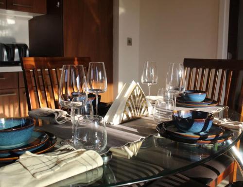 a dining table with glasses and plates on it at Custom House Square Penthouse in Belfast
