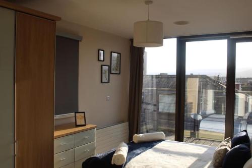 a bedroom with a bed and a large window at Custom House Square Penthouse in Belfast