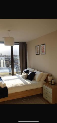 a bedroom with a large bed and a large window at Custom House Square Penthouse in Belfast