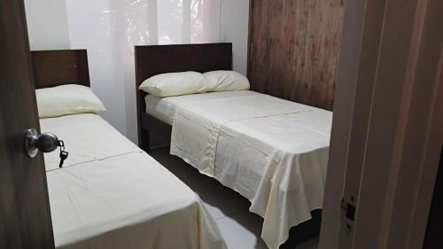 2 posti letto in una piccola stanza con lenzuola bianche di Torres de Varegal Apartamento en el corazón de Neiva a Estación El Salto