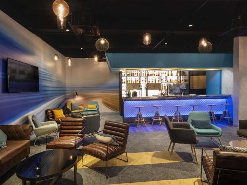 a bar with couches and chairs in a room at Novotel Le Mans in Le Mans