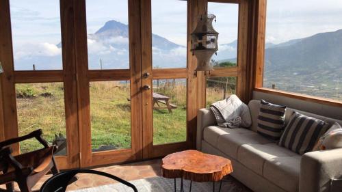 a living room with a couch and large windows at Casa ANTARA in Otavalo