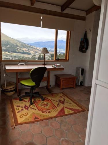 a desk and a chair in a room with a window at Casa ANTARA in Otavalo
