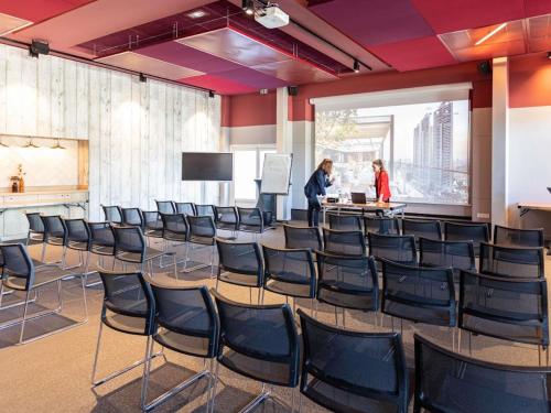 two people are standing in a room with chairs at Novotel Valence Sud in Valence