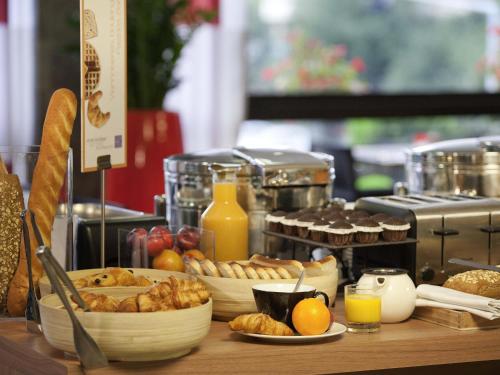 a table with various types of bread and orange juice at Novotel Roissy Saint Witz in Saint-Witz