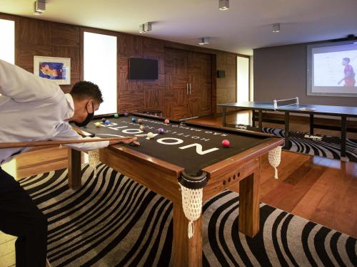 a man sitting at a pool table in a room at Novotel Sao Paulo Morumbi in Sao Paulo