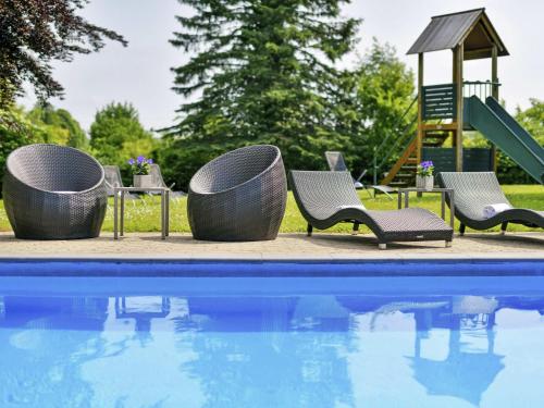 a pool with chairs and a slide next to a playground at Mercure Aachen Europaplatz in Aachen