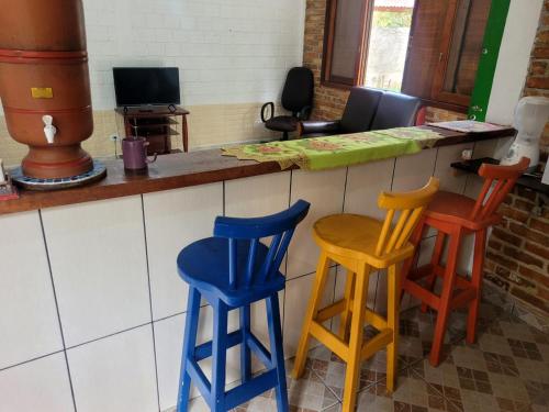 a kitchen with four colorful stools at a counter at Espaço Villa dos Anjos in Morretes