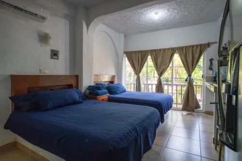 ein Schlafzimmer mit zwei Betten und einem Fenster in der Unterkunft Hotel Casa Boquita Estudios equipados con alberca y jacuzzi in Zihuatanejo