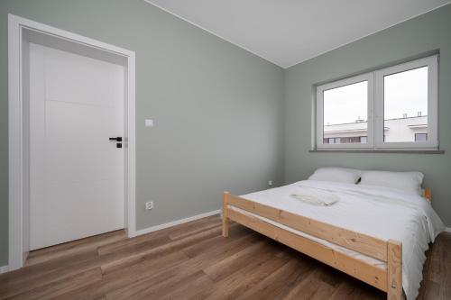 ウッチにあるŚwiętojańska Harmony Apartment by BookingHostのベッドと窓のある白い寝室