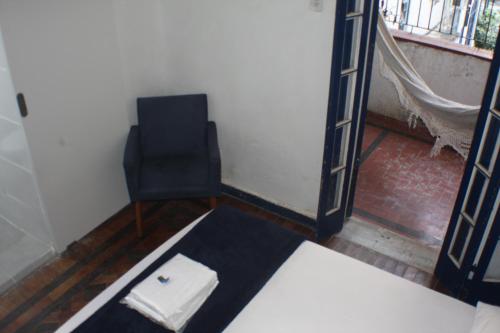 a room with a bed and a chair and a window at Farfalla Guest House in Rio de Janeiro