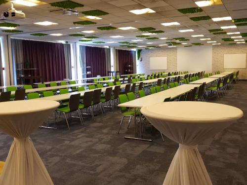 an empty lecture room with tables and green chairs at Ibis Styles Linz in Linz