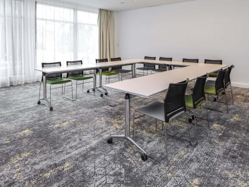 a conference room with a long table and chairs at Novotel Poznań Malta in Poznań