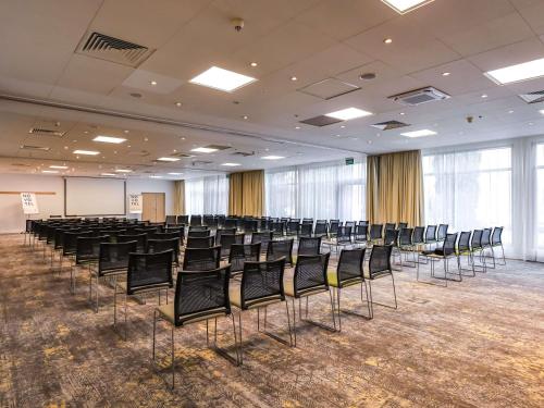 an empty room with chairs in a room with a screen at Novotel Poznań Malta in Poznań