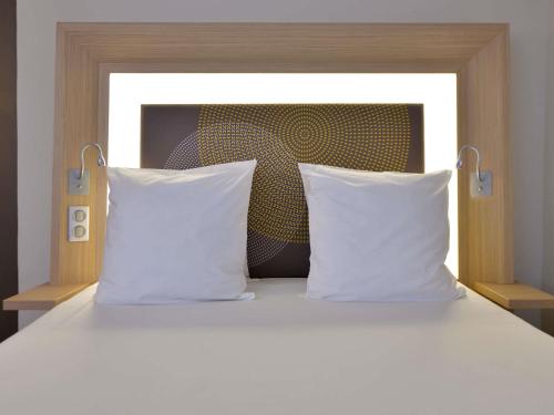 a bed with two white pillows and a headboard at Novotel Dakar in Dakar