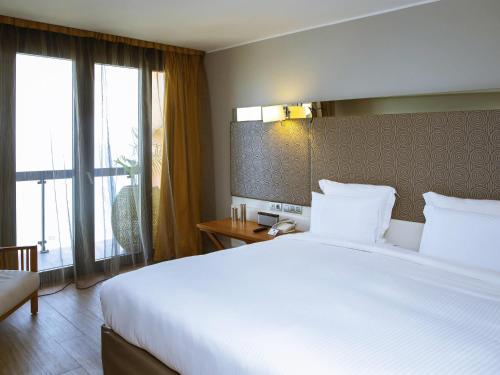 a hotel room with a large white bed and a window at Pullman Dakar Teranga in Dakar