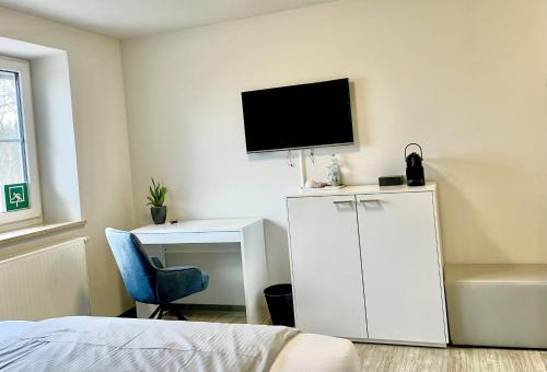 a bedroom with a tv on the wall and a desk at Das SinGold Hotel mit Highspeed WLAN und digitalem Schlüssel in Schwabmünchen