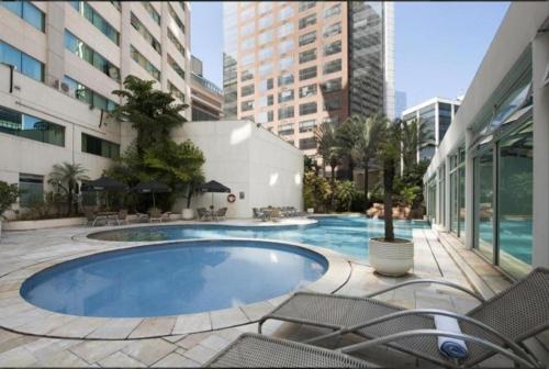 a large swimming pool in a building with chairs at Flat Conforto Luxo Vila Olimpia in Sao Paulo