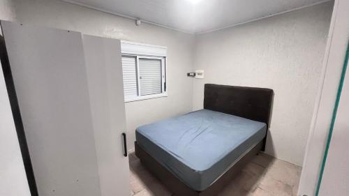 ein kleines Bett in einem kleinen Zimmer mit einem Fenster in der Unterkunft Linda casa para suas férias ! in Imbé