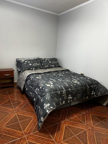 een bed met een zwart dekbed in een kamer bij Departamento Estudio, 4 personas Depto 2 in Temuco