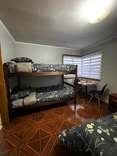 a room with two bunk beds and a table at Cómodo departamento un ambiente, Depto 2 Los Sauces in Temuco