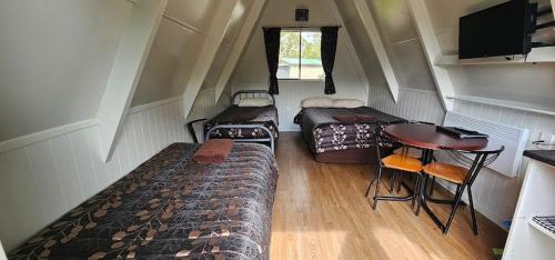 a small room with three beds and a table at Westport Kiwi Holiday Park & Motels in Westport