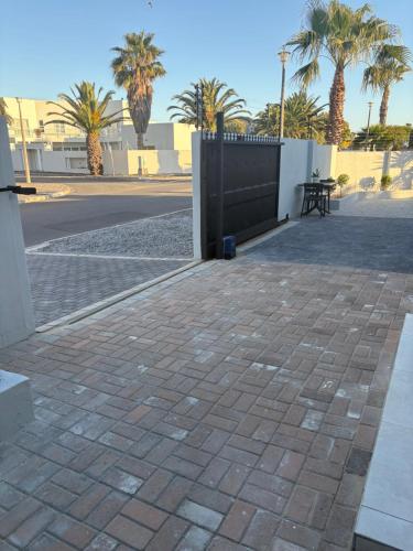 a patio with a fence and palm trees at Immaculate,Alttrative &Modern 1 Noload shedding in Cape Town