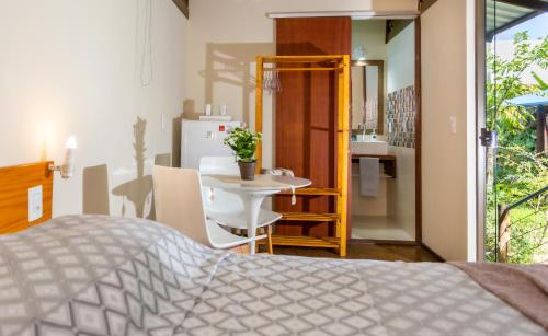 a bedroom with a bed and a table and a refrigerator at Pousada Container Eco Manguinhos in Manguinhos
