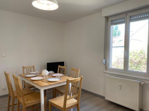 una sala da pranzo con tavolo, sedie e una finestra di City Huningue a Huningue