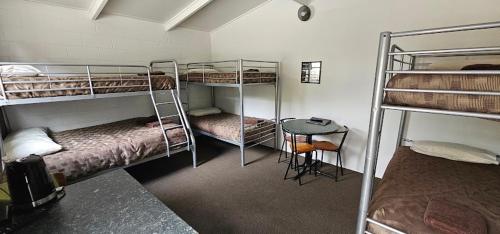 a room with three bunk beds and a table at Westport Kiwi Holiday Park & Motels in Westport