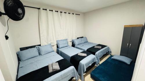 a room with three beds and a fan at Casa Família no Parque Edu Chaves in Sao Paulo