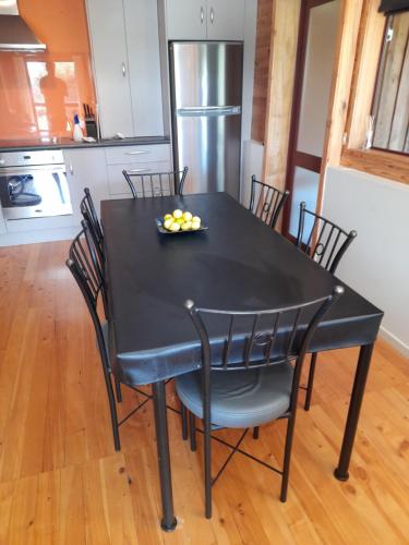 un tavolo nero con sedie e un cesto di frutta di Abel Tasman Kaiteriteri Garden & Sea View Apartment a Kaiteriteri