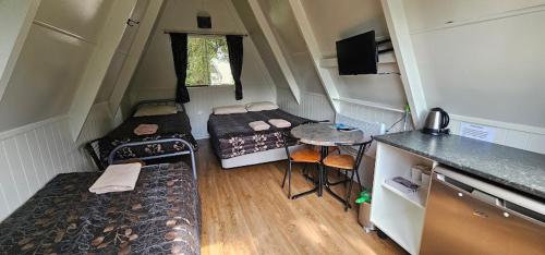 a small room with two beds and a table and a counter at Westport Kiwi Holiday Park & Motels in Westport