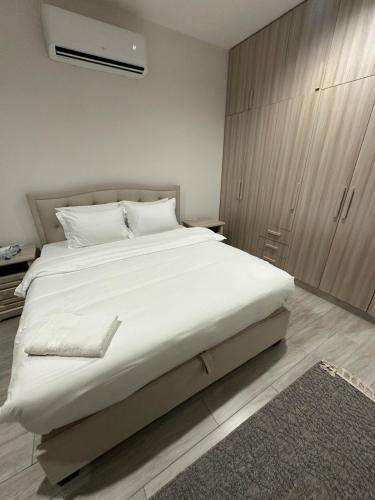 a bedroom with a large white bed and a cabinet at Moroj Al Zain - M57 in Salalah