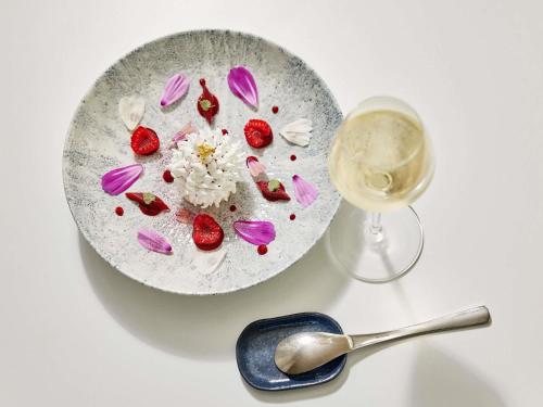 a white plate with strawberries and a glass of wine at Sofitel Golfe d'Ajaccio Thalassa Sea & Spa in Ajaccio