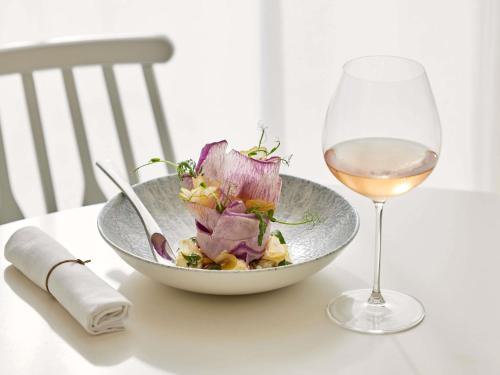 a bowl of salad and a glass of wine on a table at Sofitel Golfe d'Ajaccio Thalassa Sea & Spa in Ajaccio
