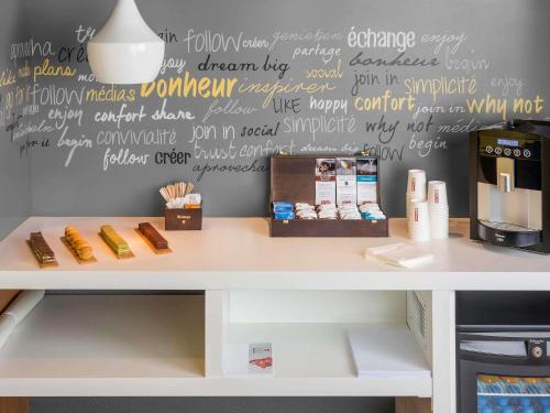a white counter with a writing on a wall at ibis Paris Porte d'Italie in Paris