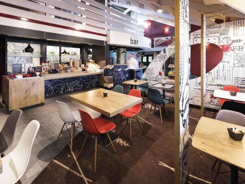 a restaurant with wooden tables and chairs and a counter at ibis Montbéliard in Montbéliard