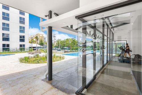 an open glass door of a building with a pool at Upstay - New Condo Just Steps Away from the Beach in Jacó