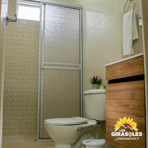 a bathroom with a toilet and a glass shower at Los Girasoles Apartamentos in Pueblo Bello