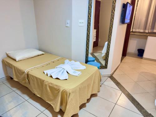 a room with a bed with towels on a table with a mirror at VA Apart Hotel Savassi in Divinópolis