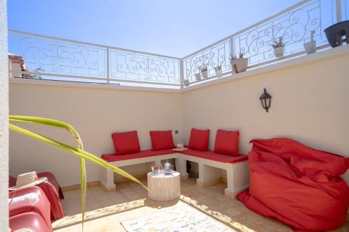 a room with red cushioned chairs and a table on a balcony at Résidence alqaria assiyahiya in Marrakech