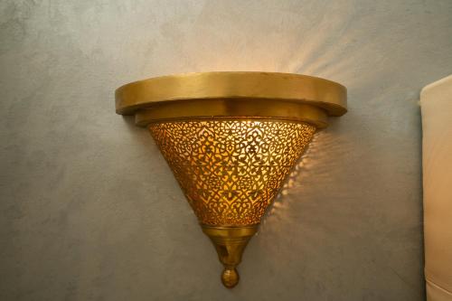 a gold light on a wall with a wall at Résidence alqaria assiyahiya in Marrakech